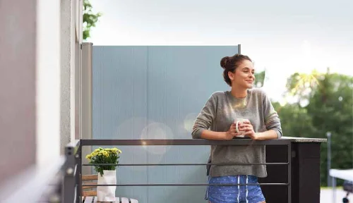 Frau auf Balkon mit blauer Seitenmarkise als Sichtschutz