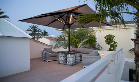Moderne Dachterrasse mit stilvollen Möbeln und großem Sonnenschirm bei Abenddämmerung